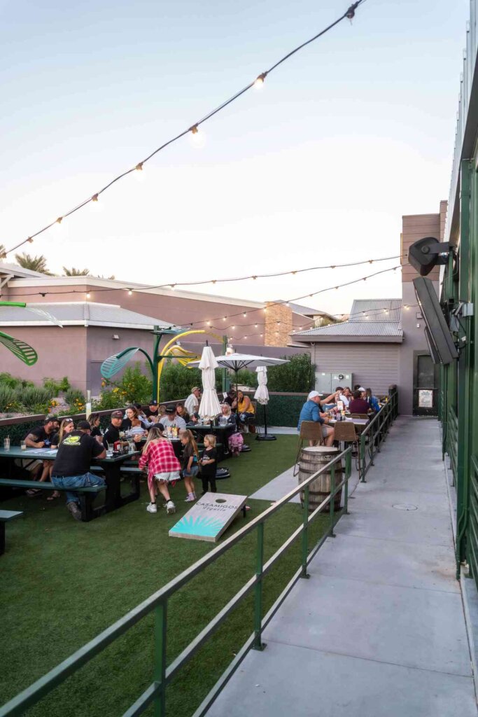 Families enjoying the outdoor area at Backyard Desert Ridge with cornhole and games, perfect for a fun day out.
