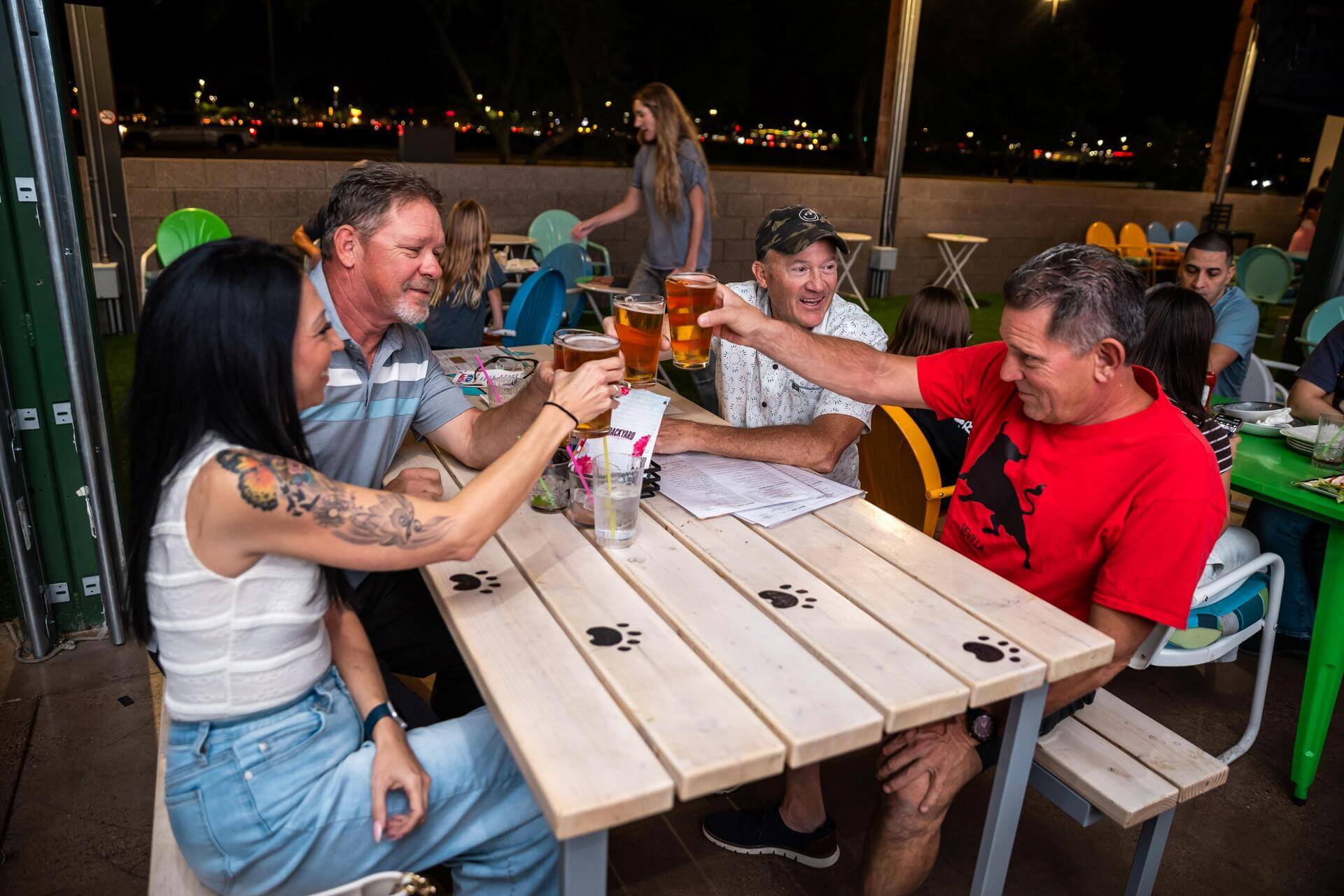 Four friends cheers their beers at Backyard Desert Ridge, enjoying drinks and a lively hangout atmosphere.